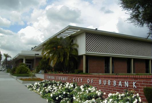 Exterior of Burbank Central Library. A mid-century modern building with a white facade, latticed screens, and brick accents. 