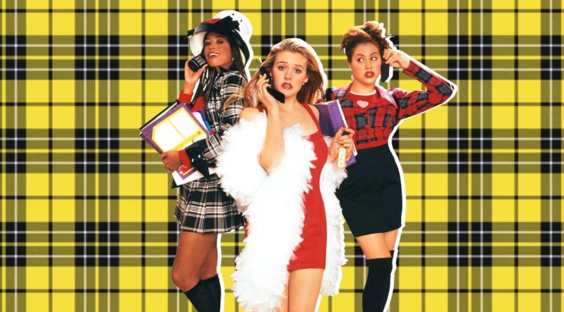 Clueless movie scene. Three women posing in front of a yellow grid background, one in a plaid outfit holding books, one in a white feather boa and red dress, and one in a red-and-black plaid top and black skirt.