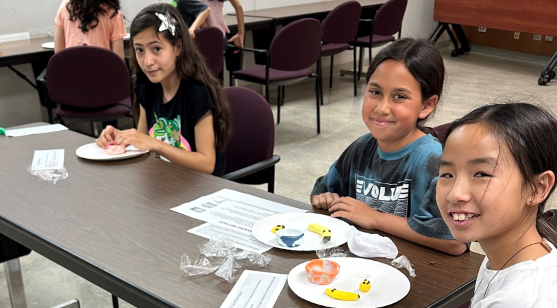 Smiling tween girls working on crafts at a table