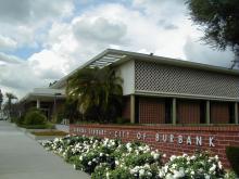 Exterior of Burbank Central Library. A mid-century modern building with a white facade, latticed screens, and brick accents. 